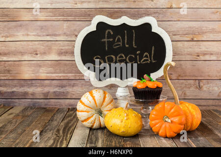 Segno della lavagna con muffin di zucca e coloquintidi ornamentali Foto Stock