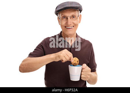 Felice senior immergendo un cookie in una tazza isolata su sfondo bianco Foto Stock