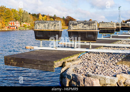 Floating rig di ormeggio sul molo in autunno. Contenitori rettangolari montati su pali metallici sono utilizzati come floater quando in acqua. Foto Stock