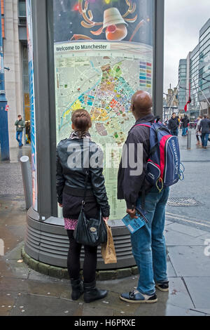 Uomo e donna che guarda la grande strada esterna mappa, Manchester, Regno Unito Foto Stock