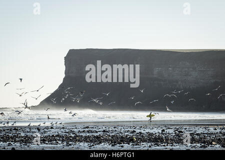 Surfer sulla spiaggia con la tavola da surf a Saltburn dal mare, North Yorkshire, Inghilterra, Regno Unito. Foto Stock