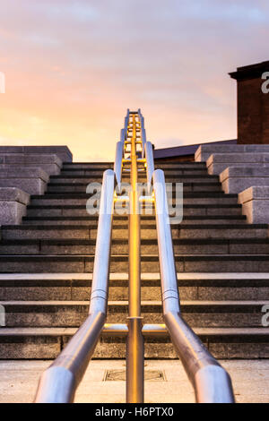 Metallo lucido corrimano illuminato dal di sotto al tramonto sulla scalinata di Piazza Granaio, King's Cross, London, Regno Unito Foto Stock