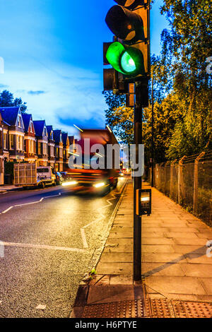 Blu e arancione urban scena notturna con un moto-sfocato camion che si avvicinano ad un semaforo verde in primo piano, Archway Road, London, Regno Unito Foto Stock