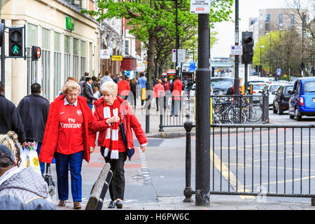 Due anziani di sesso femminile i tifosi dell'Arsenal in conversazione, camminando lungo la strada di Nag la testa, Holloway, Londra, Regno Unito, il giorno della partita Foto Stock