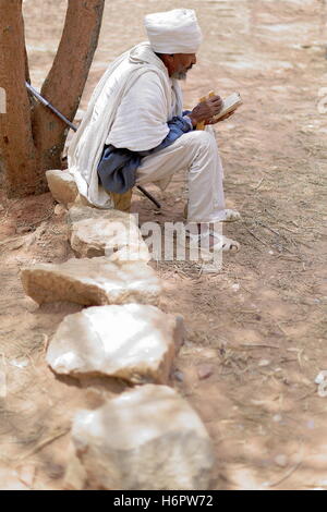 WUKRO, ETIOPIA-marzo 29: ortodossa etiope devoto barbuto uomo con il bianco gabi dress legge un libro sacro mentre seduto su pietra Foto Stock