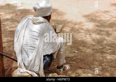 WUKRO, ETIOPIA-marzo 29: ortodossa etiope uomo devoto con il bianco gabi dress legge un libro sacro mentre seduto su una pietra. Foto Stock