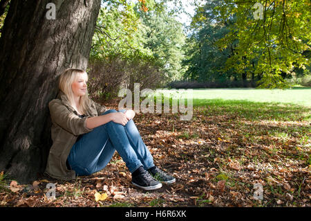 Giovane donna seduta nel parco Foto Stock