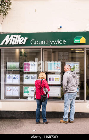 Due persone che guardano i beni di un Agenti Immobiliari finestra in Falmouth, Cornwall. Foto Stock