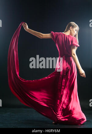 Ragazza bionda holding coulisse di abito rosa Foto Stock