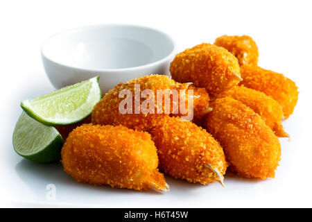 Pila di panate surimi chele di granchio con vuoto recipiente dip e le fette di limone isolato su bianco. Foto Stock