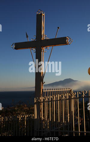 Segno della Croce sul Monte Vesuvio visto in background è avvolta nella nebbia di ringhiere metalliche circostanti la protezione incrociata il male. Foto Stock