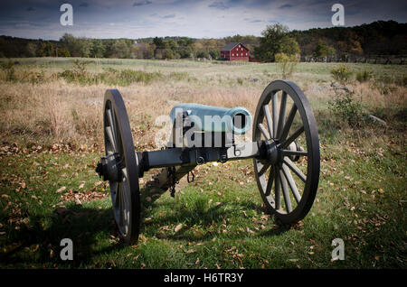 La guerra civile era il cannone sul Cimitero Ridge in Gettysburg, Pennsylvania con un granaio rosso in background. Foto Stock