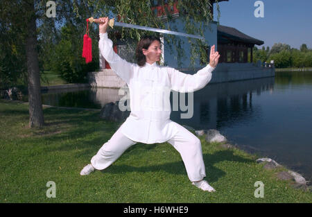 Donna, inizio 40s, facendo Tai Chi con la spada in un giardino cinese a Berlino Foto Stock