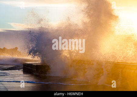 Onde enormi la frantumazione con vigore il Mornington molo frangiflutti e al tramonto. Melbourne, Australia Foto Stock