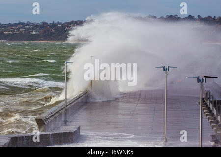 Grande onda rottura oltre il Mornington Pier e frangiflutti. Melbourne, Australia Foto Stock