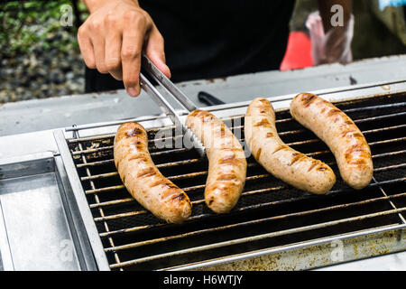 Salsiccia fresca e hot dogs grigliare all'aperto su un barbecue a gas grill. Foto Stock