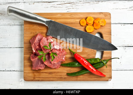 Materie carne tritata sminuzzato hacked aliment cibo crudo verde carota chef stufato di macellaio chili chili pezzi di carne arma del braccio coltello coltello Foto Stock
