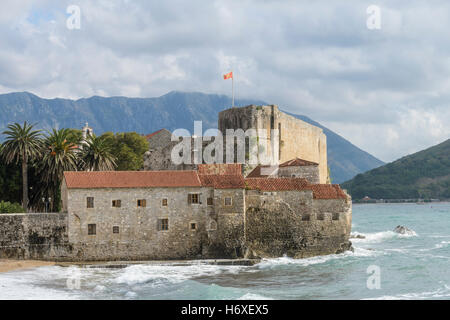 Budva, Montenegro - 21 Ottobre 2016: bandiera nazionale del Montenegro battenti alto sopra cittadella vecchia pareti durante una mareggiata è hitt Foto Stock