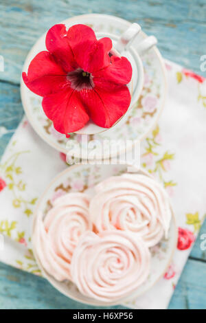 Torte di meringa nella forma delle rose in un romantico piatto con fiore rosso. Foto Stock