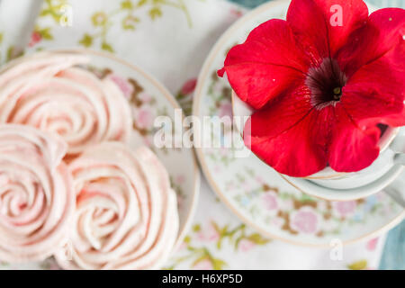 Torte di meringa nella forma delle rose in un romantico piatto con fiore rosso. Foto Stock