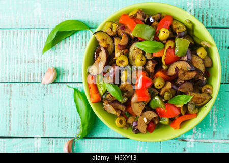 Piccante stufato di melanzane, peperoni, olive e capperi con le foglie di basilico. Vista superiore Foto Stock