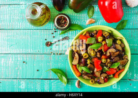 Piccante stufato di melanzane, peperoni, olive e capperi con le foglie di basilico. Vista superiore Foto Stock