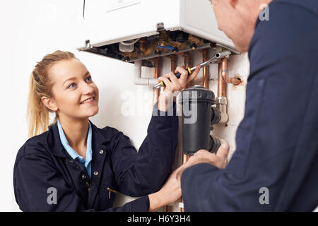 Trainee femmina Plumber lavorando sul centro di caldaia di riscaldamento Foto Stock