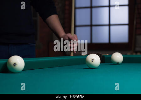 Close-up di russo gioco di biliardo nel processo: tre palle bianche sul verde tavolo da gioco panno e player con cue sullo sfondo Foto Stock