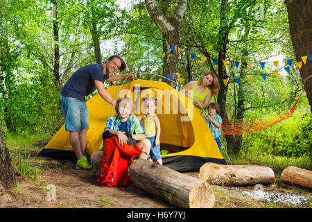 La famiglia felice mettendo su una tenda sul viaggio di campeggio Foto Stock