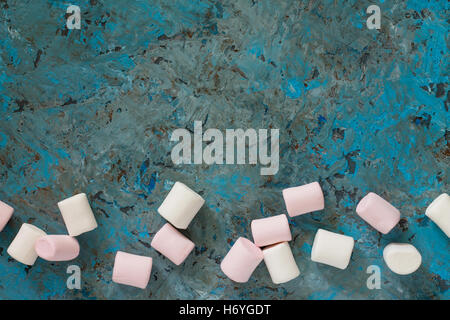 Bianco e rosa marshmallows in una ciotola di ceramica blu su sfondo di calcestruzzo. Vista da sopra. Foto Stock