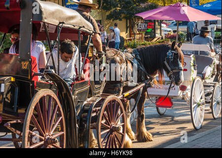 Visitatori tour Helen, Georgia, una ricreazione di un bavarese villaggio alpino, in carrozze trainate da cavalli durante l'Oktoberfest annuale. Foto Stock