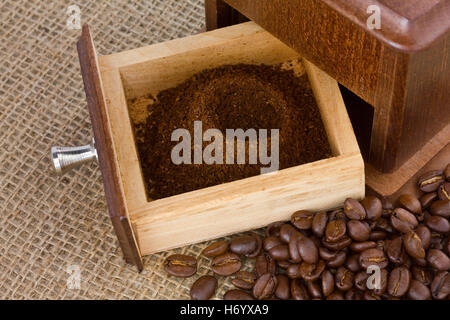 Il caffè fresco di grind nel macinino da caffè con scatola di fagioli che circonda Foto Stock