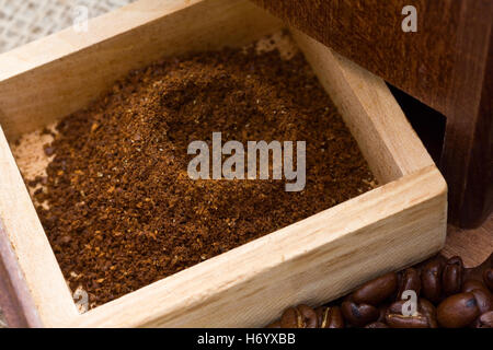 Il caffè fresco di grind nel macinino da caffè con scatola di fagioli che circonda Foto Stock