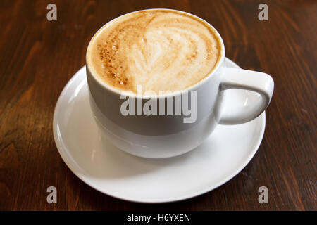 Classico cappuccino schiumoso in scuro legno zigrinato tabella. Dettaglio. Da sopra. Dettaglio. Foto Stock