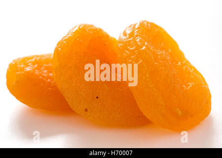 Tre le albicocche secche sulla superficie bianca con profondità di campo Foto Stock