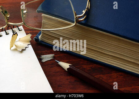 Matita con occhiali e libri su un tavolo di legno. Foto Stock