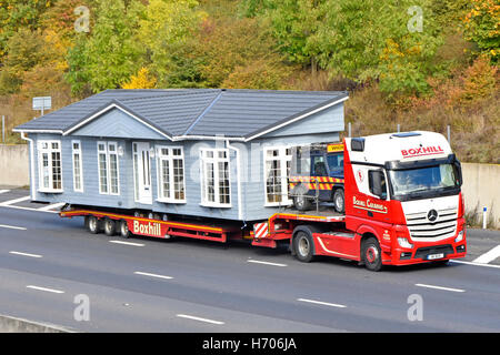 Parte del trasportatore di grandi dimensioni prefabbricato per la casa di parcheggio su autocarro articolato con caricatore basso hgv dell'autostrada britannica con auto di scorta Foto Stock