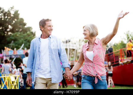 Coppia senior presso la fiera del divertimento, tenendo le mani, passeggiate. Foto Stock