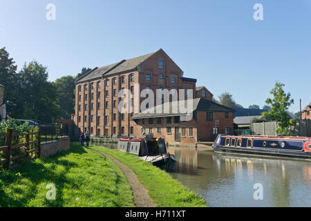 Sul Grand Union Canal a Blisworth; un vecchio cornmill, ora convertito in appartamenti in background, narrowboats in primo piano Foto Stock