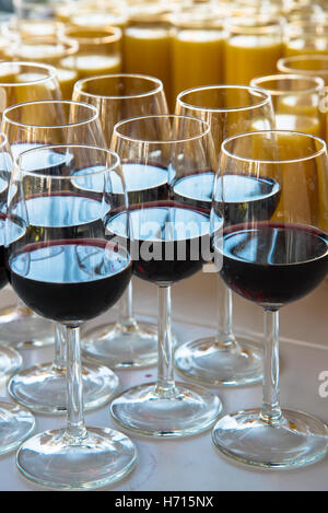 Bicchieri di vino rosso e jus d'arancia in attesa al tavolo a caso Foto Stock