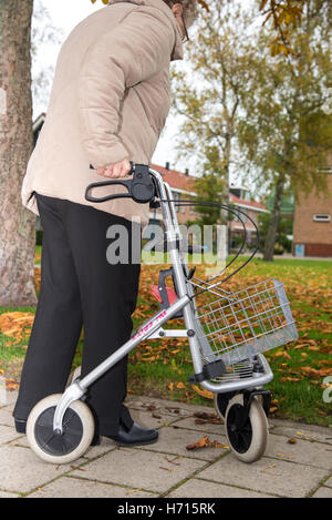 Vecchia donna con assistere camminando sul marciapiede Foto Stock