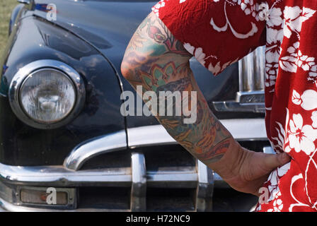 Dettaglio di un uomo tatuato con camicia hawaiana di fronte a un auto, Hot Rods, Kustoms, incrociatori & Arte al 'Bottrop Kustom Kulture Foto Stock