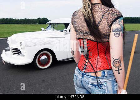 Il motorino di avviamento la ragazza con un corpetto rosso e tatuaggi accanto a una limousine bianca, Hot Rods, Kustoms, incrociatori & Arte al 'Bottrop Kustom Foto Stock