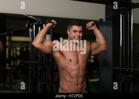 Giovane uomo è al lavoro sul suo bicipite con cavo crossover in una moderna palestra Fitness Foto Stock