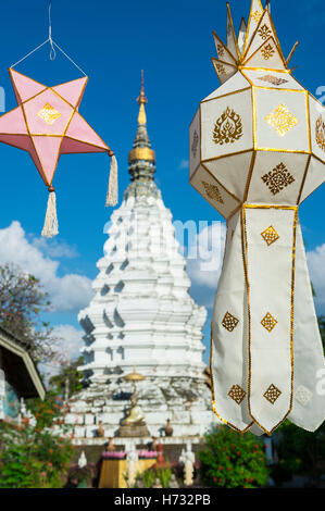 Tessuto decorativo lanterne flutter in cielo blu nella parte anteriore di un tradizionale chedi buddista torre pagoda in Chiang Mai Thailandia Foto Stock