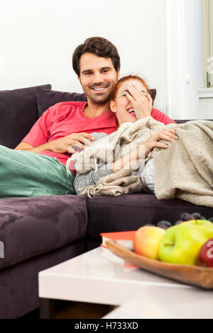 Gli amanti della giovane coppia in soggiorno sul divano mentre la lettura e la visione TV Foto Stock