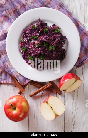 Brasato di cavolo rosso con mele e cannella vicino sul tavolo. Vista verticale da sopra Foto Stock