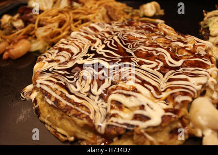 Okonomiyaki, Giapponese Pizza guarnita con scaglie di bonito, maionese e salsa barbecue sulla piastra di ferro calda a Kyoto, Giappone Foto Stock