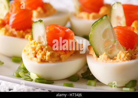 Antipasto di vacanze: uova ripiene con macro di salmone su una piastra orizzontale. Foto Stock