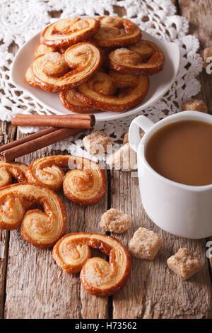 Caffè con latte e biscotti Palmiers vicino sul tavolo. In verticale Foto Stock